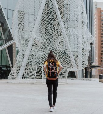 person walking toward face statue